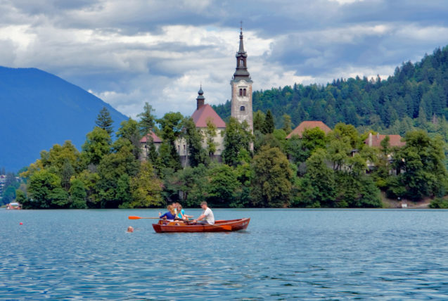 Turists in a rowboat rowing towards Bled Island in the middle of Lake Bled