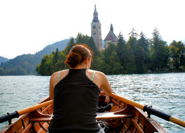 A woman in a boat at Lake Bled rowing towards Bled Island