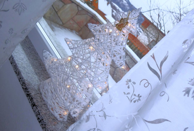 Christmas tree decoration on the window with a balcony in the background