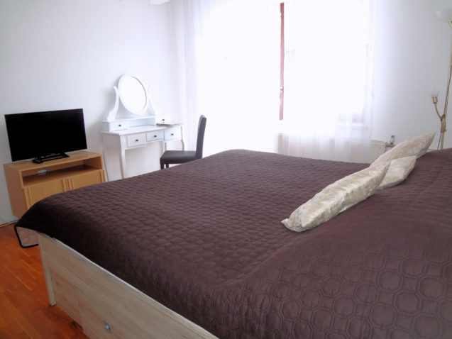 A king-size double bed and a new white dresser with mirror in Fine Stay Apartments