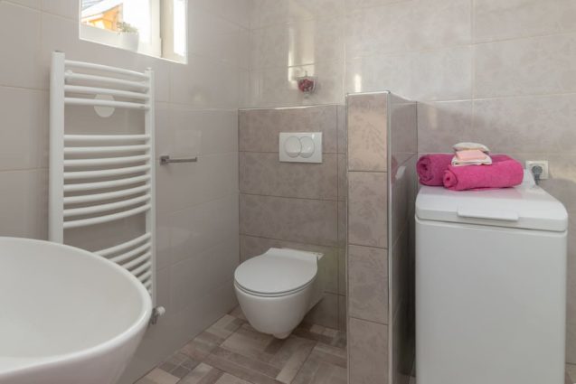 A washing machine and a toilet in the bathroom of the Modern Apartment With Balcony and Terrace, Apartments Fine Stay