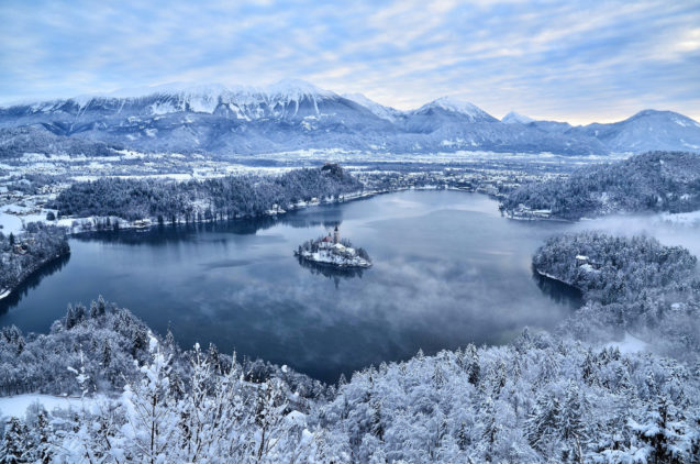 Elevated view of Lake Bled draped in winter white with a thick layer of snow in the winter