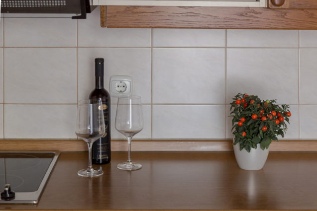 A bottle of wine with two wine glasses on a countertop in the kitchen at Apartments Fine Stay Bled