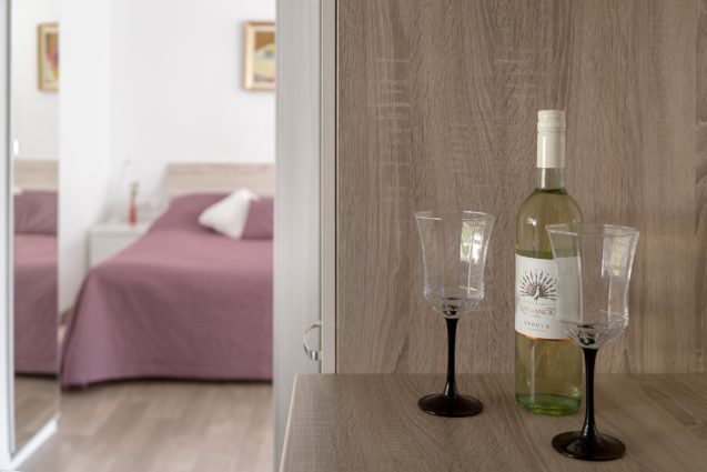 Bottle of wine in the kitchen and the double bed in the first bedroom of the Modern Apartment With Balcony and Terrace