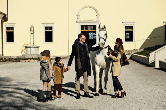 A family with a Lipizzan horse in the barnyard at Lipica Stud Farm in Slovenia