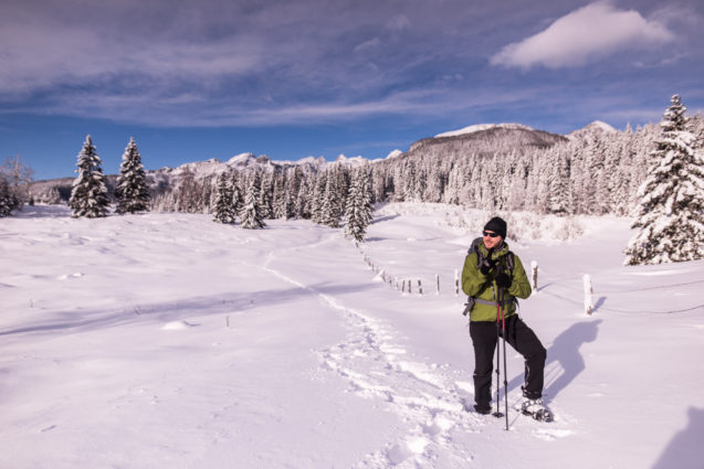 A guy with snowshoes at Pokljuka Plateau blanketed with snow in winter