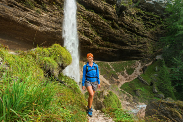 A female hiker in front of Pericnik Waterfall in Vrata Valley in Slovenia