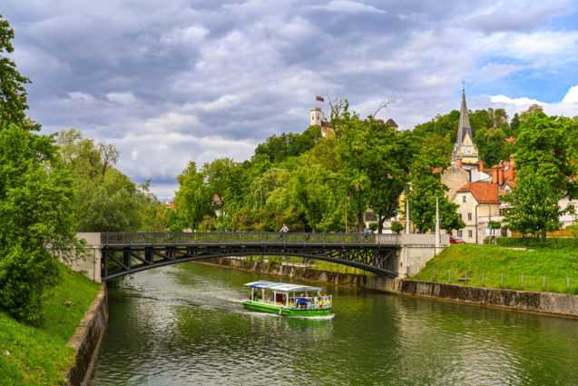 A tourist boat under the bridge in the Ljubljanica River in Ljubljana, Slovenia