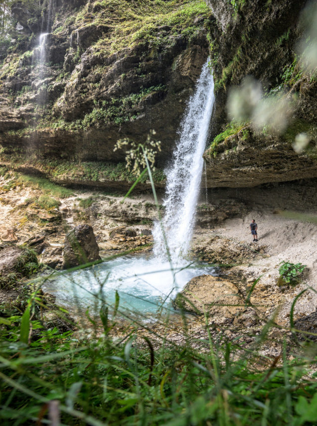 A hiker behind Upper Pericnik Waterfall in Vrata Valley in Slovenia