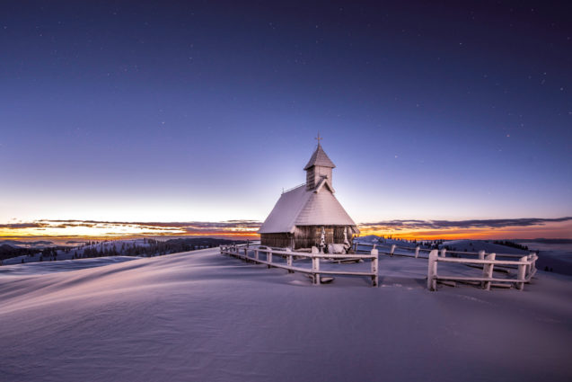 Old wooden church at Velika Planina blanketed with snow in winter