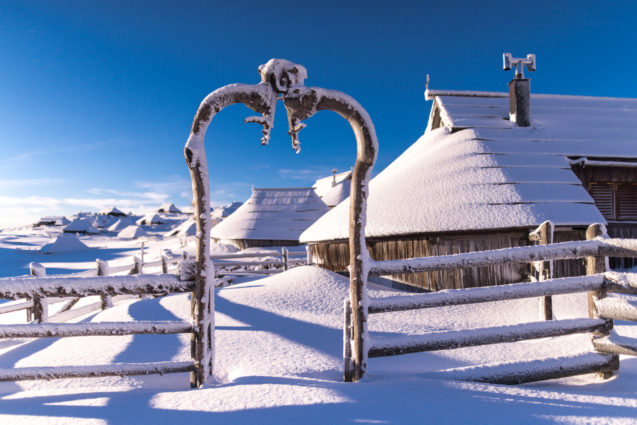 A shingle-roofed, semicircular wooden hut at Velika Planina blanketed with snow in winter