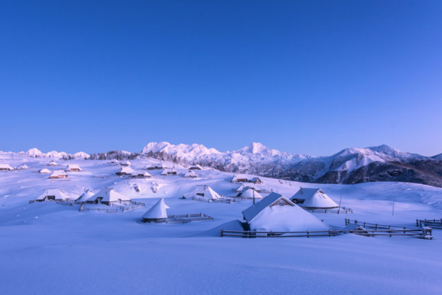 Shingle-roofed, semicircular wooden huts at Velika Planina in Slovenia blanketed with snow in winter