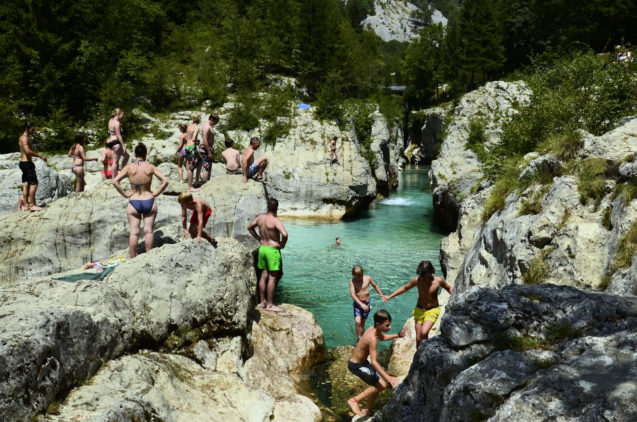 A group of people swimming an sunbathing in Soca Gorge in Slovenia