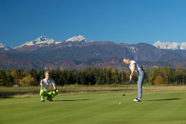 A female golfer at Royal Bled Golf course with Mt. Triglav in the background