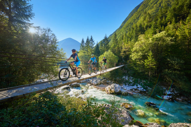 A female cyclists crossing the suspension bridge over the Soca River in Slovenia