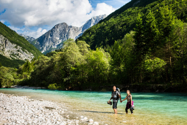 A couple of hikers walking in the Soca River in Slovenia