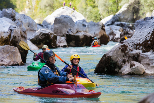 A group of watersports enthusiasts kayaking on Soca River in Slovenia