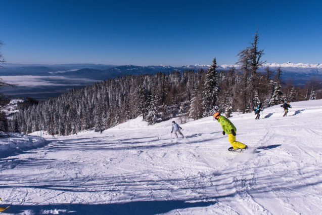 Skiers at Krvavec Ski Resort on a sunny winter day with clear blue sky