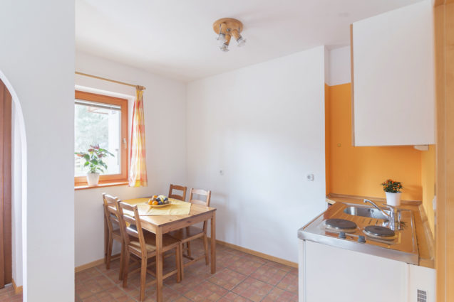 A dining table with 4 chairs and a kitchenette in Duplex Apartment with Balcony at Apartments Valant Bled in Slovenia