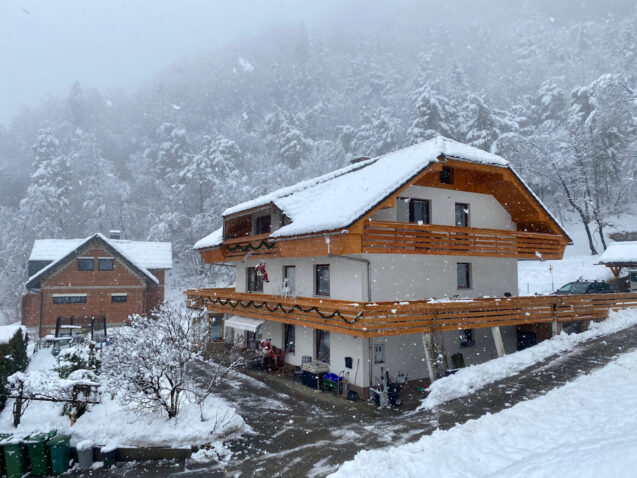 Exterior of the larger house of accommodation Apartments Fine Stay covered in snow in winter