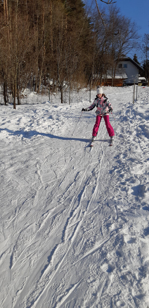 Children skiing on a slope behind accommodation Fine Stay Apartments in the Bled area of Slovenia